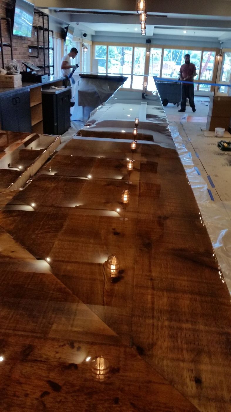 Finished reclaimed wood bar top running the length of a restaurant under cage lights