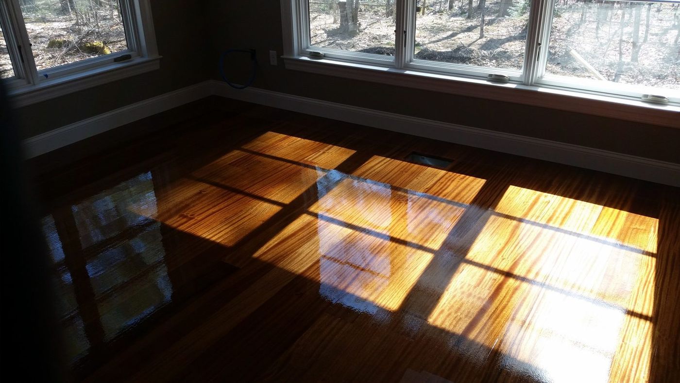 Mahogany floor with a ribbon-striped grain lit by sunlight through a row of windows
