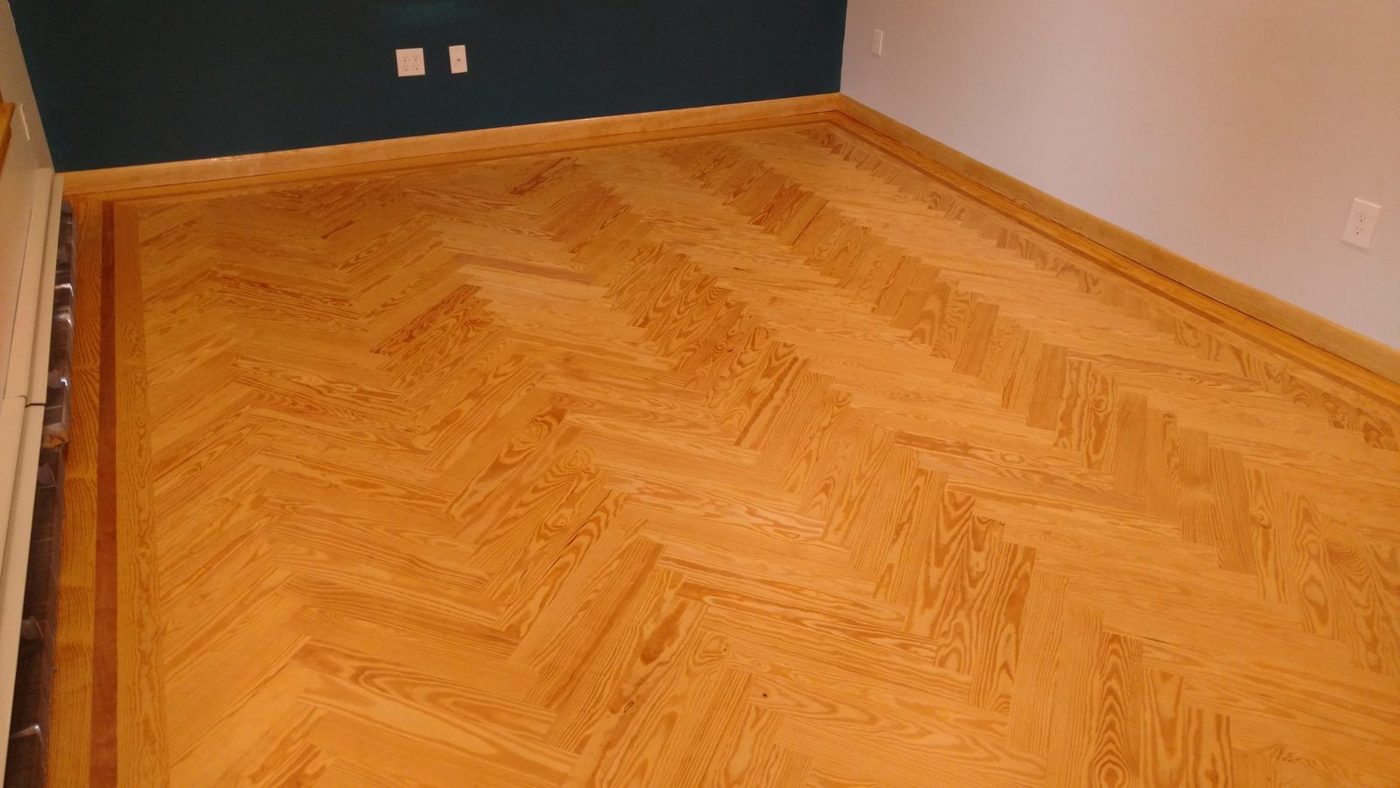 Southern yellow pine herringbone floor with a border band, finished in a warm amber